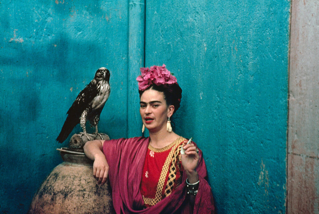 friday kahlo with cigarette and pet eagle on brilliant blue wall, photograph