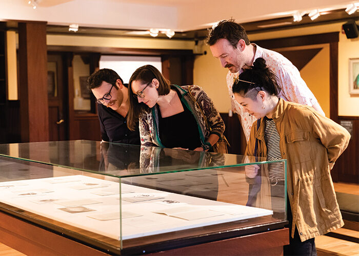 Photograph of four people looking at a glass case display in the museum.